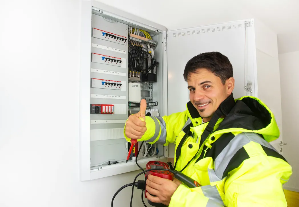 Lachende elektricien bij een geopende groepenkast